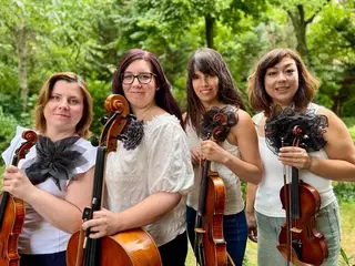 A Surprise String Quartet négy tagja hangszereikkel a szabadban, fák előtt