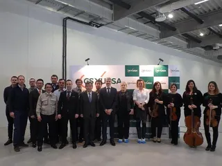Csoportkép a vendégekkel és a vonósnégyessel a GS Yuasa feliratú fal előtt