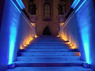 Kék fénnyel megvilágított díszlépcső gyertyákkal, fent karácsonyfa
