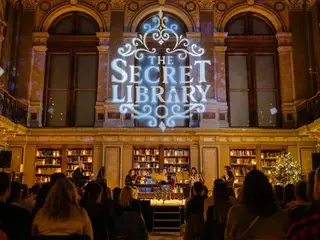 The Secret Library felirat a színpad fölött, előtérben a közönség