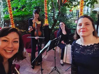Szelfi a vonósnégyesről az étterem teraszán, fényfüzérekkel és kottatartókkal